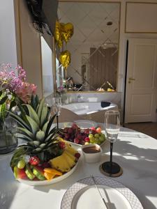a table with a plate of fruit and a glass of wine at Apartament z Jacuzzi Nova Bydgoszcz in Bydgoszcz