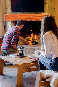 a man and a woman sitting at a table in front of a fireplace at Tillka - Casas de Montaña in Villa La Angostura