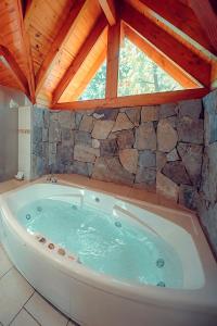 a large bath tub in a room with a stone wall at Tillka - Casas de Montaña in Villa La Angostura