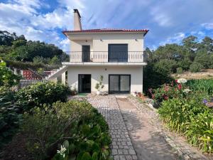 a white house with a balcony and a walkway at Casa do Rio in Freixieiro de Soutelo
