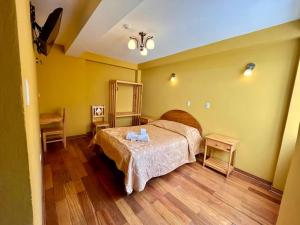 a bedroom with a bed and two tables in it at Hostal Cactus in Cusco