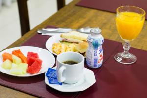 a table with two plates of food and a cup of juice at Imperial Suzano Shopping Hotel in Suzano