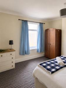 a bedroom with a bed and a window with blue curtains at 52 - room 3 - smart TV in Swansea