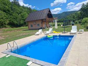 a large swimming pool with chairs and a house at Vikendica Mandic in Gornji Volari