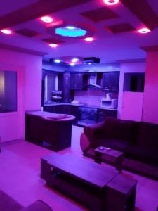 a living room with a couch and a kitchen with purple lights at شقة 24 in Irbid