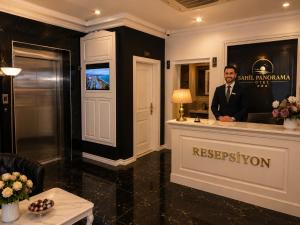 a man in a suit standing at a reception desk at Sahil Panorama Otel in Trabzon