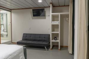 a bedroom with a couch and a tv on the wall at Cocles Green Studios in Cocles