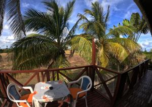 a table and chairs on a deck with palm trees at White Coconut Studio in Christ Church