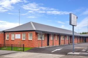a red brick building with a sign in front of it at Newington Apartments in Ballarat
