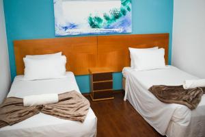 two beds in a room with blue walls at Imperial Suzano Shopping Hotel in Suzano +13 photos