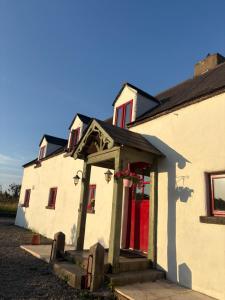 a white building with a red door and red windows at THE FARMHOUSE Room 1 in Balcunnin