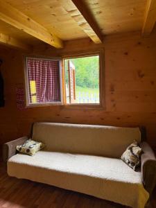 a couch sitting in a room with a window at Planinska Koliba Mo in Katun Božički
