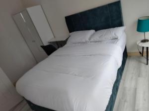 a large white bed in a room with a blue lamp at The Place CABIN in Coleraine +1 photo