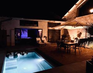 a house with a swimming pool and a table and a tv at Appartement avec jacuzzi et piscine sur les remparts in Langres