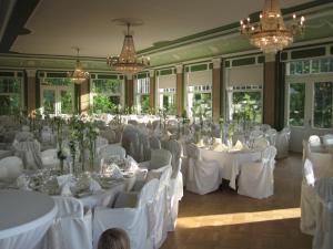 ハイデルベルクにあるシュロスホテル モルケンクールの白いテーブルと椅子、シャンデリアが備わる宴会場