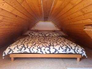 a bed in a room with a wooden ceiling at Apartma Pod orehom in Slap ob Idrijci