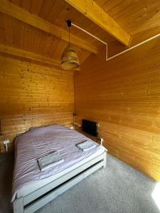 a bedroom with a bed in a wooden wall at Srebrny Domek in Ostroszowice +16 photos