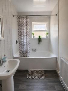 a white bathroom with a tub and a sink at 52 - room 4 - city view in Swansea