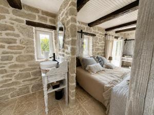 a bedroom with a bed and a stone wall at Le Petit Refuge - La Petite Longère in Rahon +77 photos