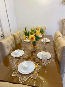 a table with plates and glasses and a vase of flowers at Zensean Haven in General Santos