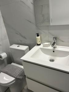 a white bathroom with a toilet and a sink at Arco Boutique Apartments in Paralio Astros
