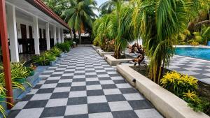 a resort walkway with a checkerboard floor and a swimming pool at Coconut Leaf Shadow Guest in Nilaveli