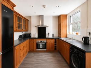 a kitchen with wooden cabinets and a black refrigerator at 52 - room 2 - smart TV in Swansea