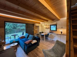 a living room with a blue couch and a kitchen at Chata Pod Dubem Kameňák in Moravany