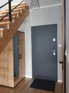a hallway with a blue door and wooden stairs at MazuryTime in Mrągowo