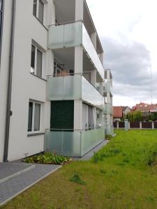 an apartment building with a balcony and a yard at MazuryTime in Mrągowo