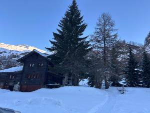 a house in the snow with trees in front of it at Chalet historique de haut standing in La Tour