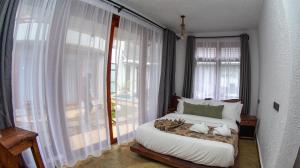 a bedroom with a bed and a large window at Olarashii River Lodge in Arusha +16 photos