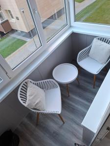 two chairs and a table in a room with two windows at Atokvėpis sielai in Šilutė