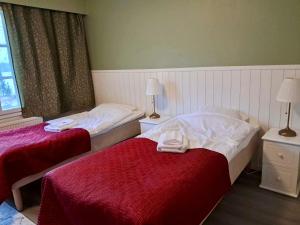 a hotel room with two beds with red sheets at Rajaniemen Pappila in Virrat +24 photos