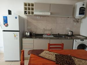a kitchen with a refrigerator and a sink and a table at Mi Refugio Venado in Venado Tuerto