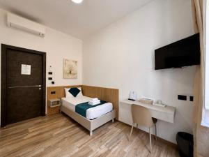 ein Schlafzimmer mit Bett, Schreibtisch und Fernseher in der Unterkunft CHD Rooms in Ancona