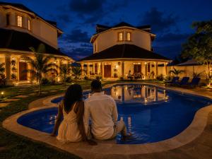 a couple sitting next to a pool in front of a house at Greenfield Villa D- Diani in Diani Beach