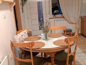 a dining room table with chairs and a vase of flowers at Apartma Deni in Jelšane
