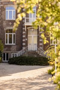 a large brick building with a white door and stairs at Historisch herenhuis voor 12 personen met volledig ommuurde tuin in Oudenaarde +56 photos