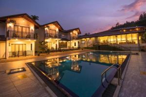 a large house with a swimming pool in front of it at Okwin Resort Nawalapitiya in Kandy