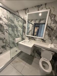 a bathroom with a sink and a toilet and a mirror at Skylux Hotel - Long Island City in Queens