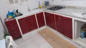 a kitchen with red cabinets and a sink at Appartement près de la corniche in Sousse