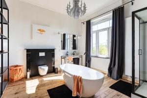 a bathroom with a large white tub and a fireplace at Historisch herenhuis voor 12 personen met volledig ommuurde tuin in Oudenaarde