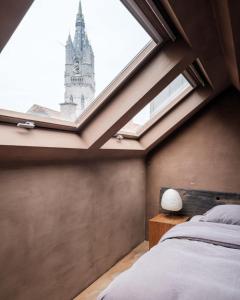 a bedroom with a large window with a clock tower at Wabi Guesthouse in Ghent
