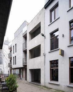 a white building with black windows on a street at Wabi Guesthouse in Ghent