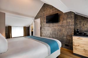 a bedroom with a large bed and a tv on a wall at Hotel & Restaurant Maison Pal'Ange in Durbuy +121 photos