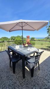 a table with an umbrella and a chair under it at Country House L'Oliveto in Marta