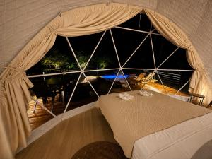 a bedroom with a bed with a large window at Kupolica glamping dome in Brčko