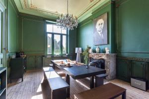 a green room with a table and a fireplace at Historisch herenhuis voor 12 personen met volledig ommuurde tuin in Oudenaarde