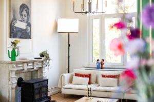 a living room with a white couch and a fireplace at Historisch herenhuis voor 12 personen met volledig ommuurde tuin in Oudenaarde